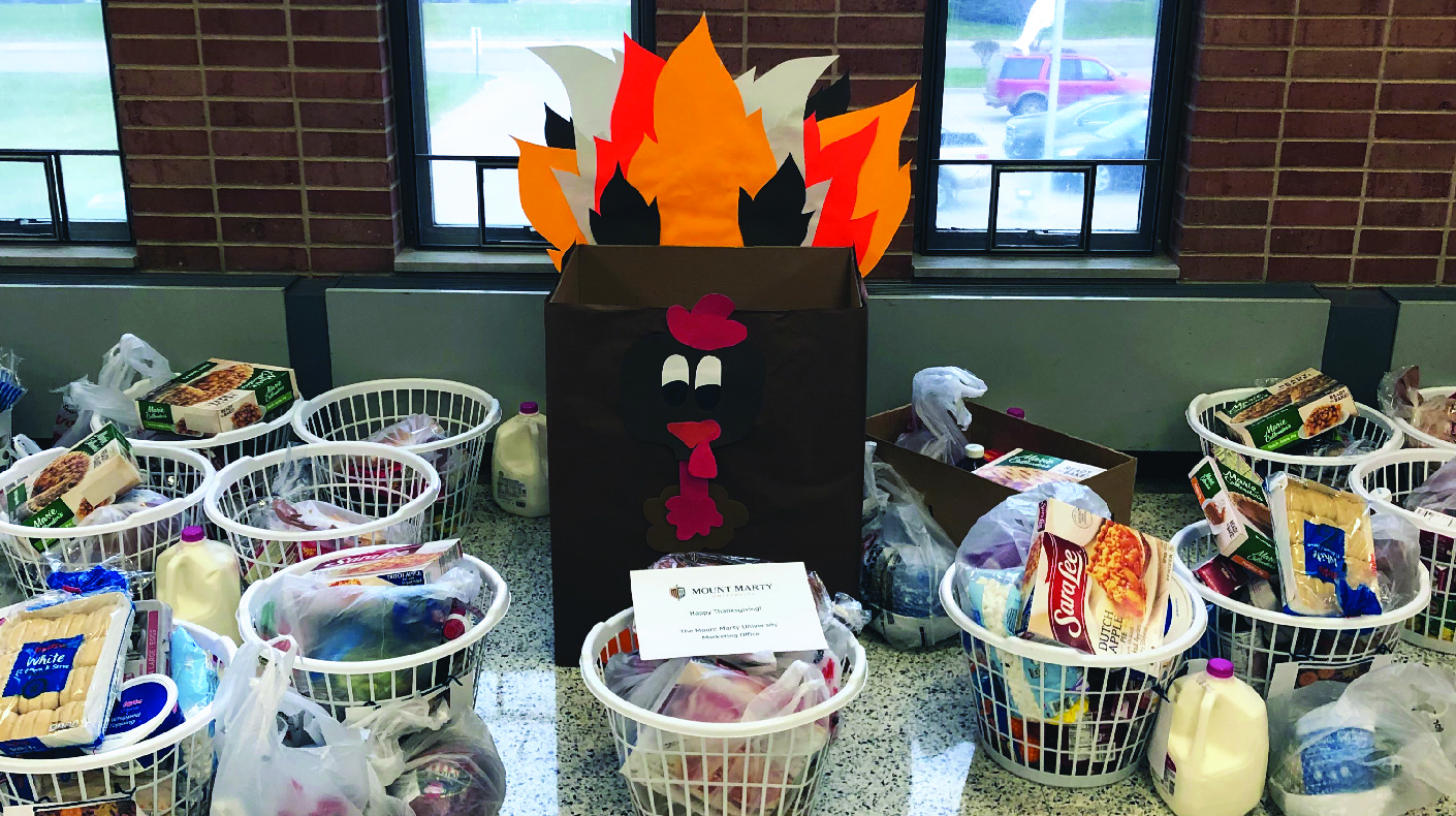 Thanksgiving Baskets gathered in front of cardboard turkey.